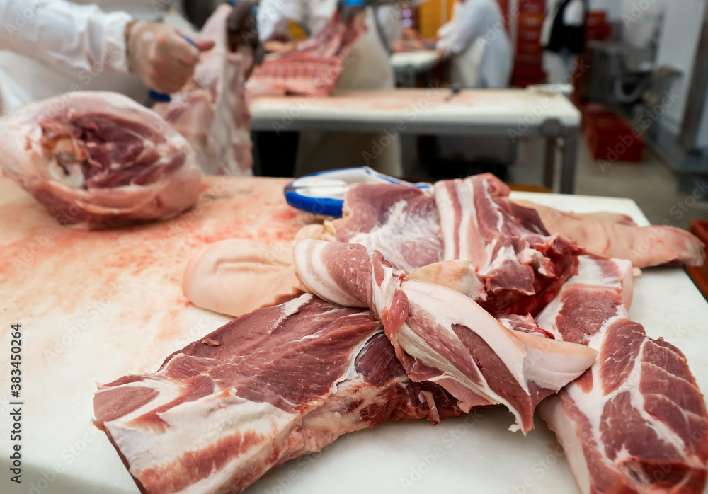 Sliced pork pieces lie on the table of a meat processing plant