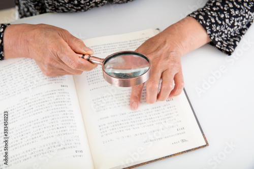 Фотография The elderly are reading books with a magnifying glass in hand