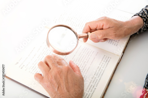 Canvastavla The elderly are reading books with a magnifying glass in hand