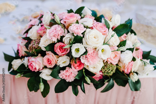 Big bouquet of fresh flowers, pink, white roses and greenery in vase. Wedding flowers, bridal bouquet closeup. Home decor on table, vintage style. Decoration objects.