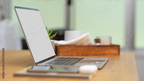 Workspace with mock up laptop, smartphone and supplies on wooden table