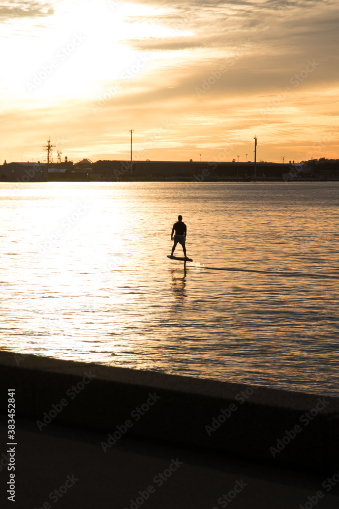 Silhouette of a man on a surfboard hydrofoil on the ocean at sunset
