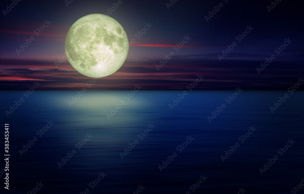 Full Moon with dark cloud in night sky and seascape view in background. (Elements of this image furnished by NASA.)