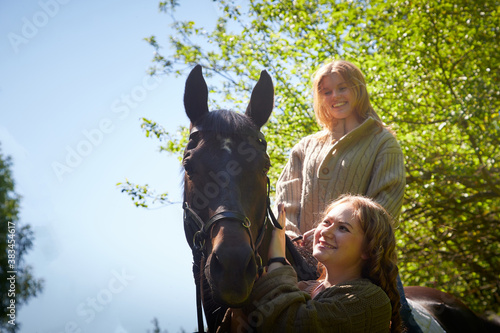 Two girls with big horse in a summer day