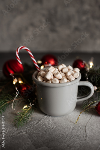 Christmas Setting with Hot Chocolate in a Fancy Sweater Mug with Marshmallows, Candy Canes, Wooden Deer and Xmas Lights on the Background