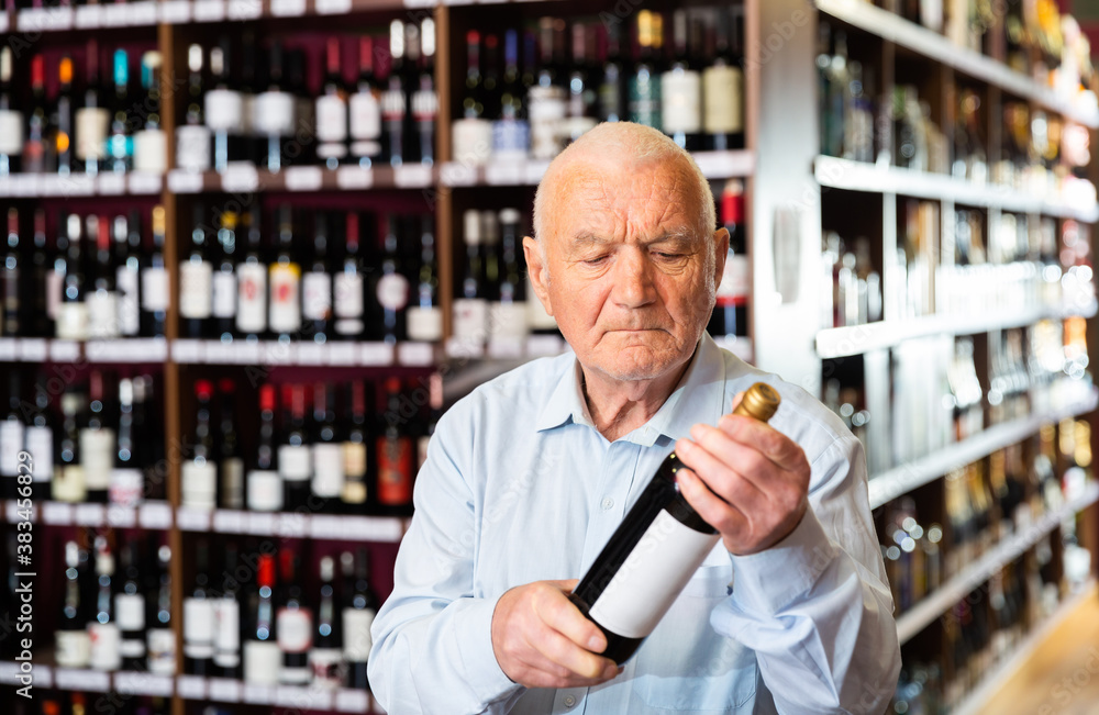 Portrait of senior man visiting winehouse in search of bottle of good wine. High quality photo