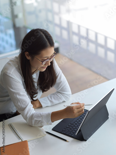 Businesswoman working on her project while using tablet in workspace