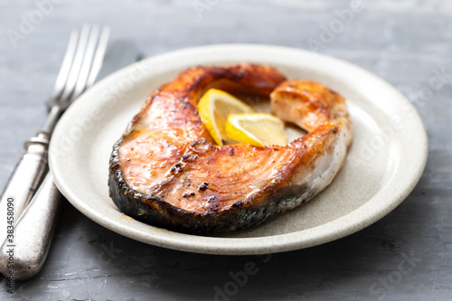 fried salmon with lemon on the dish on ceramic background