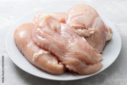 raw chicken breast with black pepper on white plate