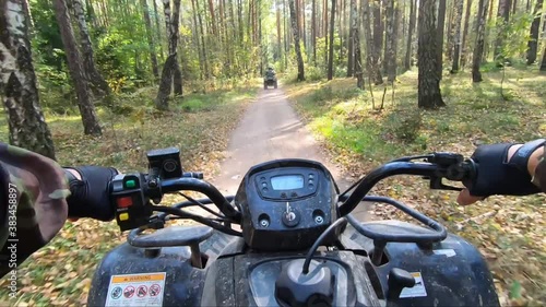 Quad bike ride on the road through sunny summer forest. First-person view photo