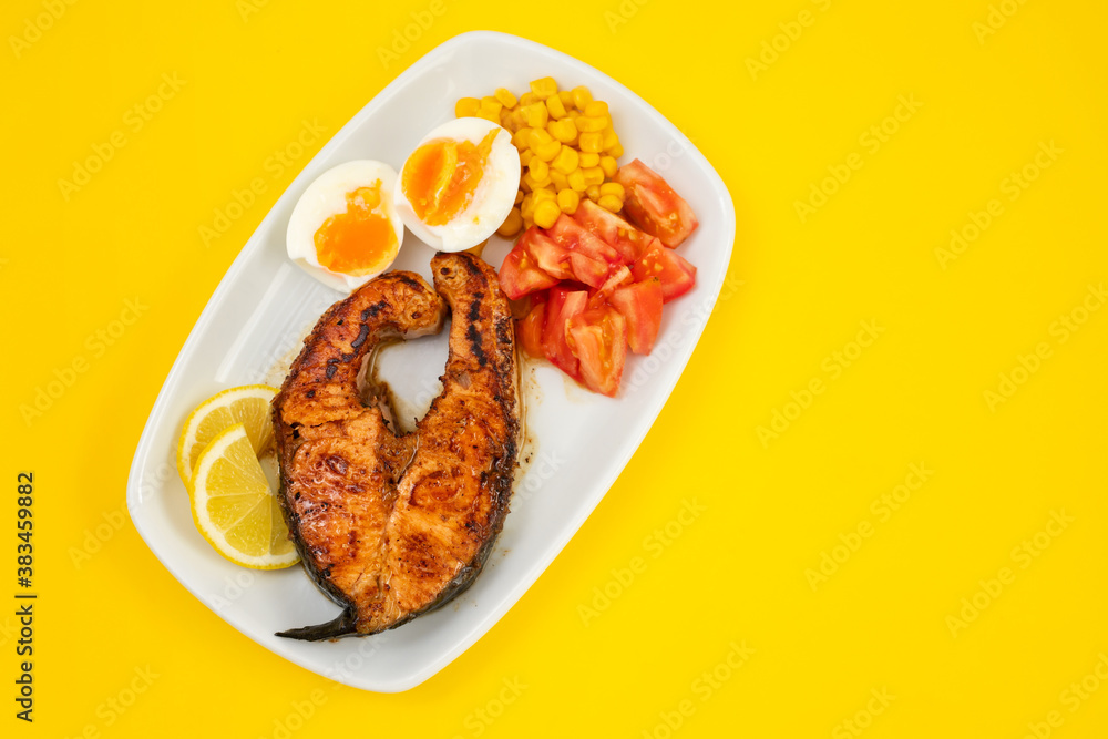 fried salmon with boiled egg and vegetables on white dish