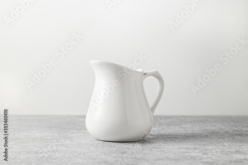 beautiful vintage milk jug of white color on a light concrete background

