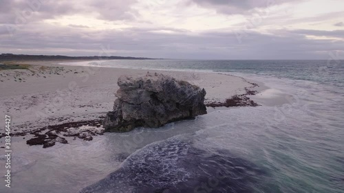 Huge rock formation at the beach in Western Australia during sunrise with stormy clouds in the background.
