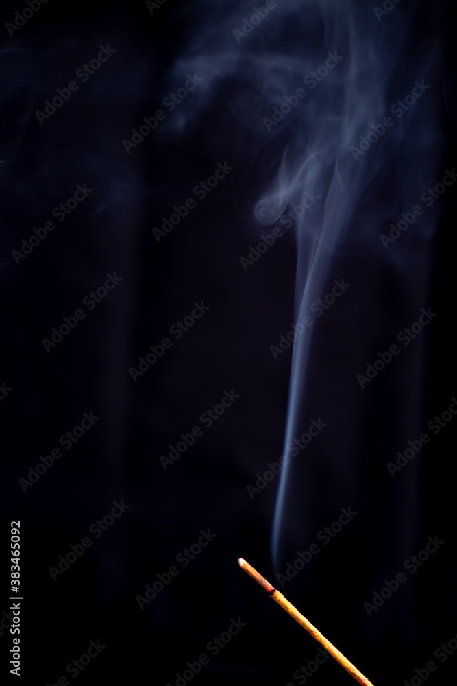 Incense stick with a wisp of smoke. On a dark background Incense stick with a wisp of smoke. On a dark background