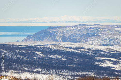 Beautiful northern nature. Landscape with snow covered mountain slopes. The end of April in the north-east of Russia. The coast of the Sea of ​​Okhotsk. Magadan Region, Siberia, Russian Far East.