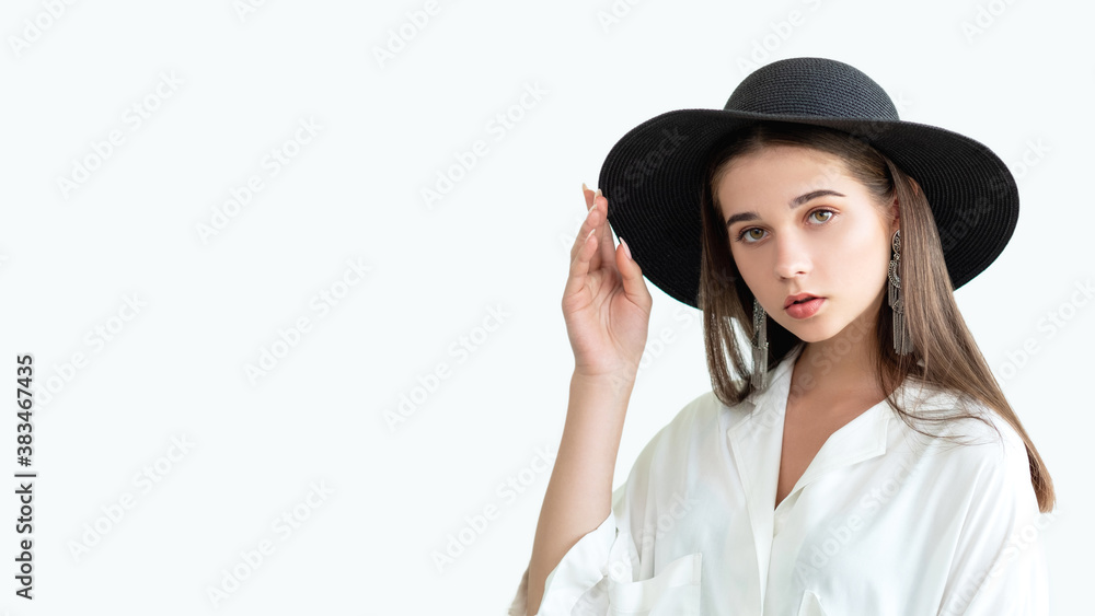 Trend summer outfit. Casual boho style. Beautiful woman in wide-brimmed black hat vintage earrings white blouse. Looking at camera isolated on neutral copy space. Female elegance. Fashion model look Trend summer outfit. Casual boho style. Beautiful woman in wide-brimmed black hat vintage earrings white blouse. Looking at camera isolated on neutral copy space. Female elegance. Fashion model look