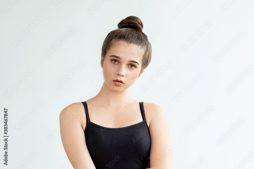 Home outfit. Casual look. Pretty young woman in black sleeveless top and bun hairstyle looking at camera isolated on neutral. Aesthetic cosmetology. Beauty treatment Home outfit. Casual look. Pretty young woman in black sleeveless top and bun hairstyle looking at camera isolated on neutral. Aesthetic cosmetology. Beauty treatment