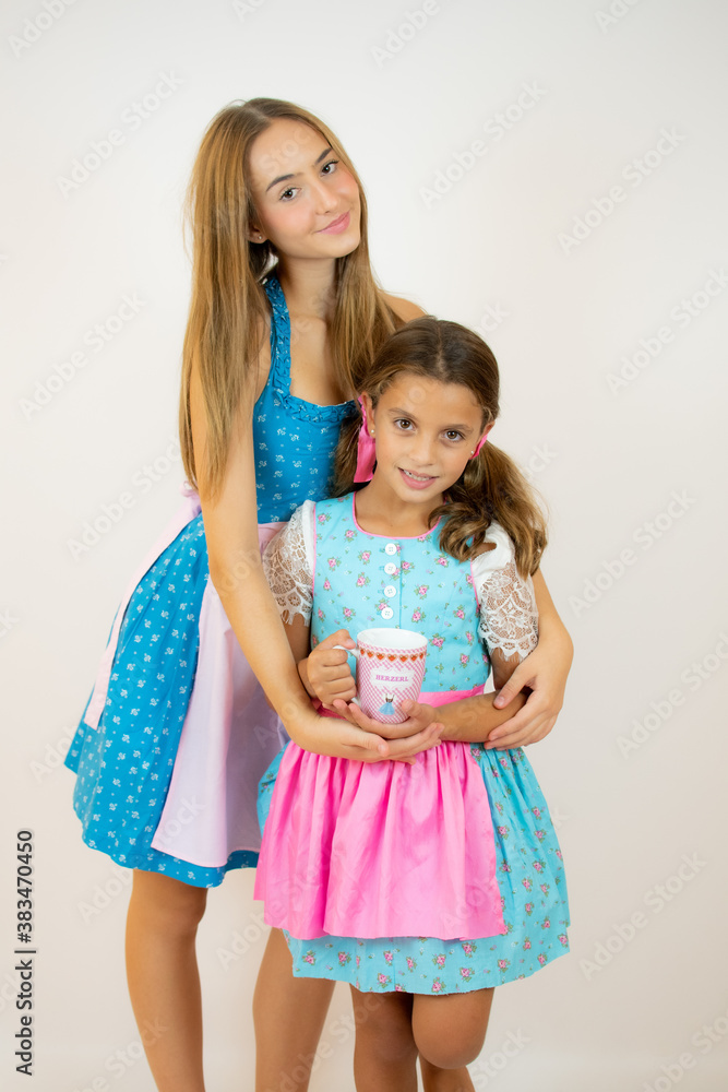 Two happy bavarian girls in dirndl dress over white background Two happy bavarian girls in dirndl dress over white background