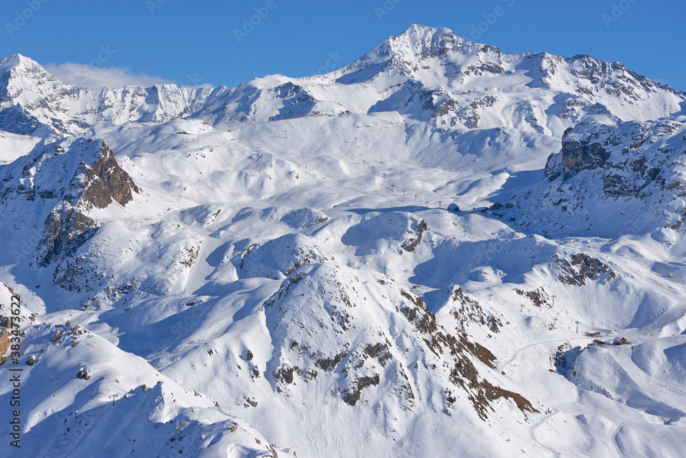 View of the ski slopes and lifts on the mountains near Tignes high-altitude ski resort in France during the winter season.