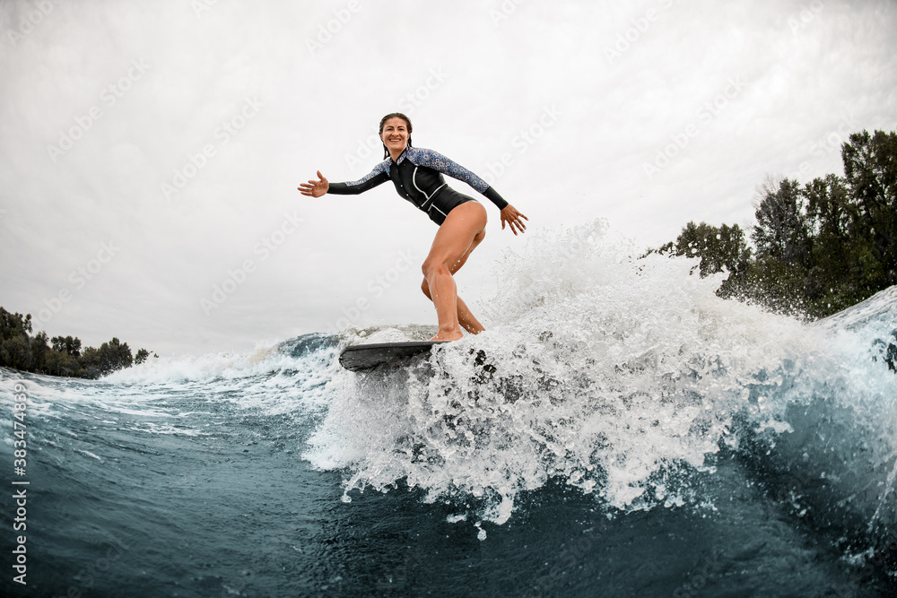 handsome woman stands on a surfboard and professionally rides on the wave