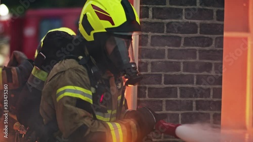 two firefighters extinguishing fire, burning house. High quality 4k footage photo