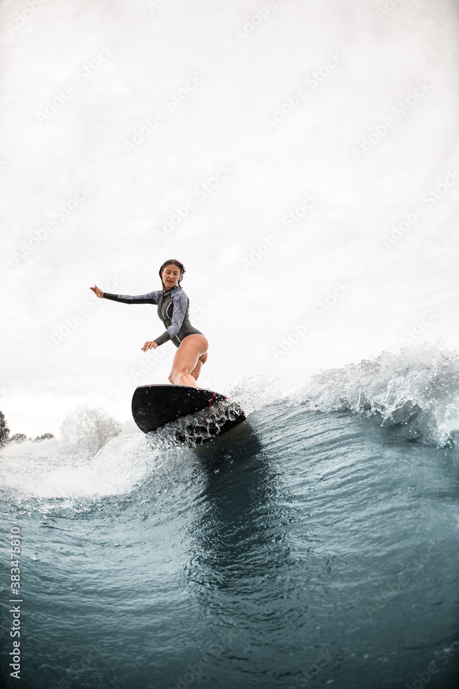 View on woman who stands on a surfboard and rides on the wave View on woman who stands on a surfboard and rides on the wave