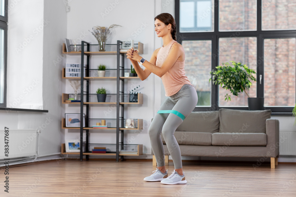 Fototapeta premium sport, fitness, lifestyle and people concept - happy woman exercising with resistance band at home