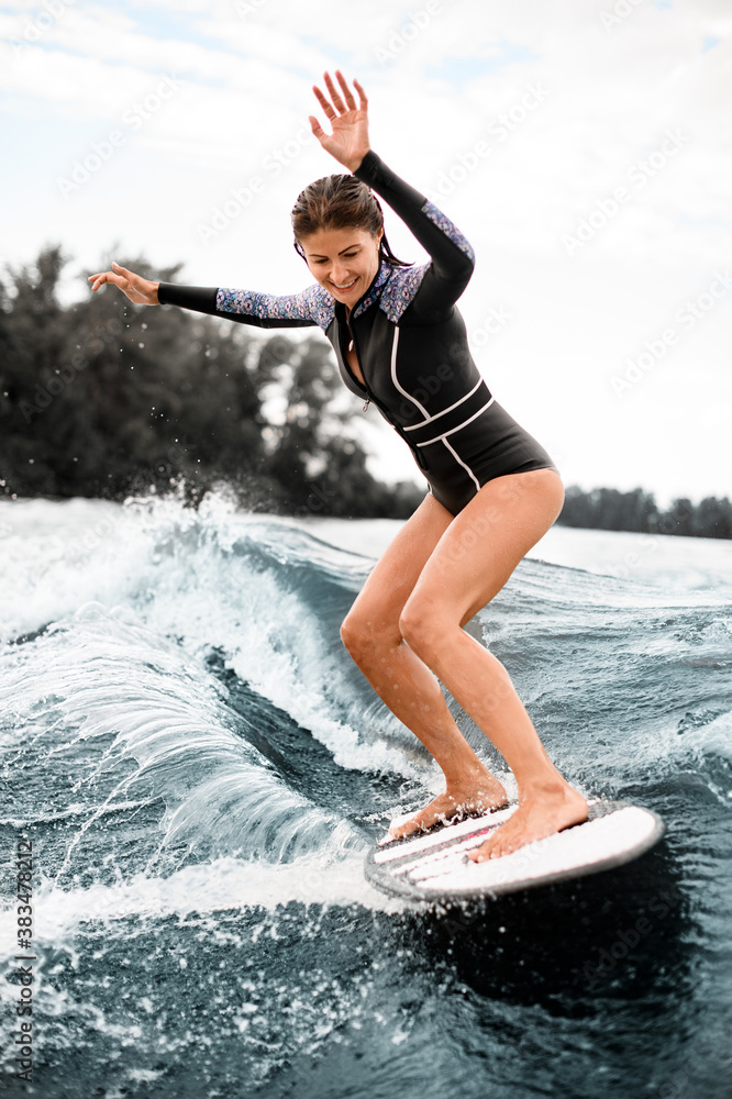nooit een kopje Uitdrukkelijk smiling woman stands on surfboard and balances on wave from motor boat  Stock Photo | Adobe Stock