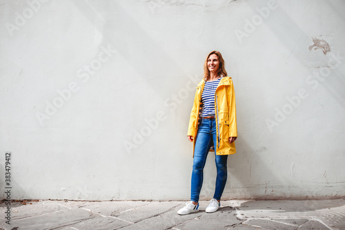 happy woman standing on the street in front of a wall