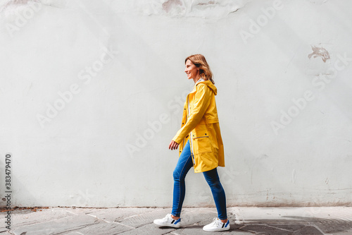 happy woman walking on the street in front of a wall