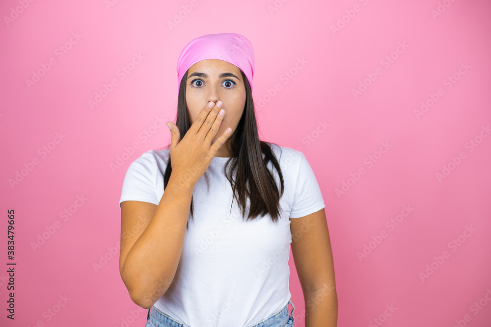 Young beautiful woman wearing pink headscarf over isolated pink background surprised covering her mouth Young beautiful woman wearing pink headscarf over isolated pink background surprised covering her mouth