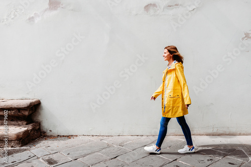 happy woman walking on the street in front of a wall