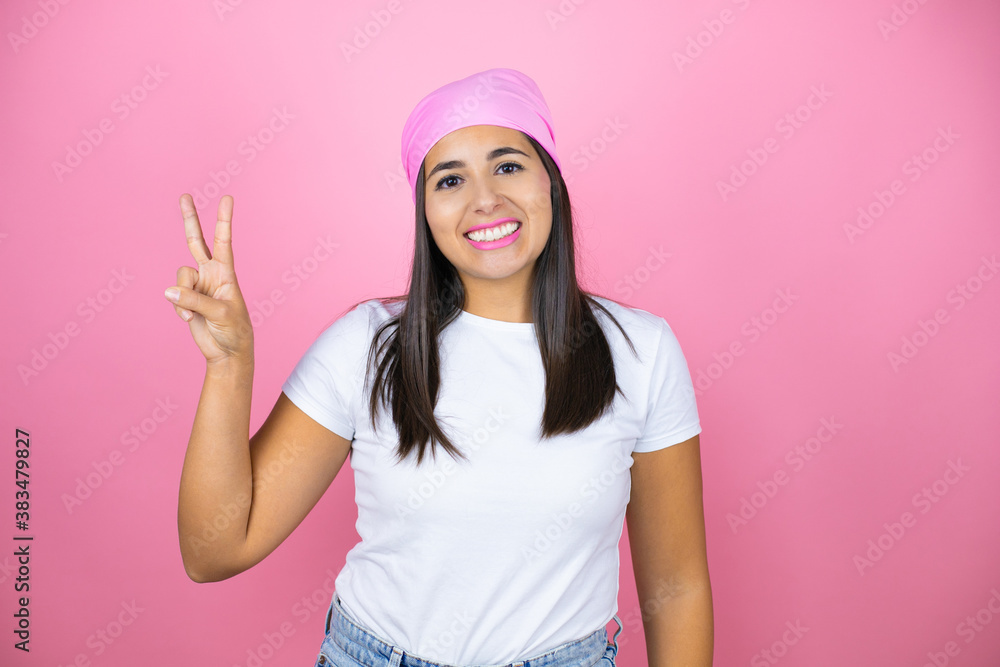 Young beautiful woman wearing pink headscarf over isolated pink background showing and pointing up with fingers number two while smiling confident and happy Young beautiful woman wearing pink headscarf over isolated pink background showing and pointing up with fingers number two while smiling confident and happy