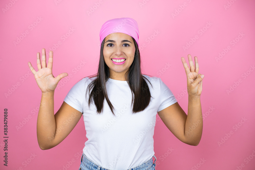 Young beautiful woman wearing pink headscarf over isolated pink background showing and pointing up with fingers number eight while smiling confident and happy Young beautiful woman wearing pink headscarf over isolated pink background showing and pointing up with fingers number eight while smiling confident and happy