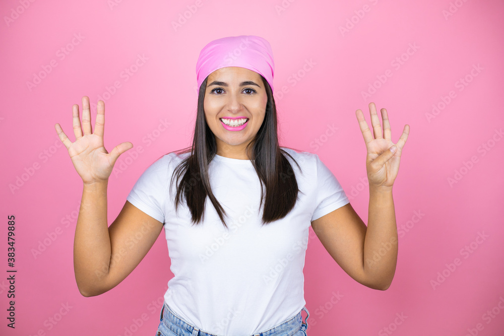 Young beautiful woman wearing pink headscarf over isolated pink background showing and pointing up with fingers number nine while smiling confident and happy Young beautiful woman wearing pink headscarf over isolated pink background showing and pointing up with fingers number nine while smiling confident and happy