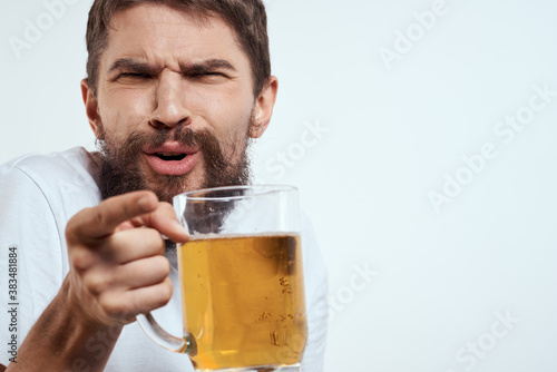 man with a mug of beer in his hands and a white t-shirt light background mustache beard emotions model