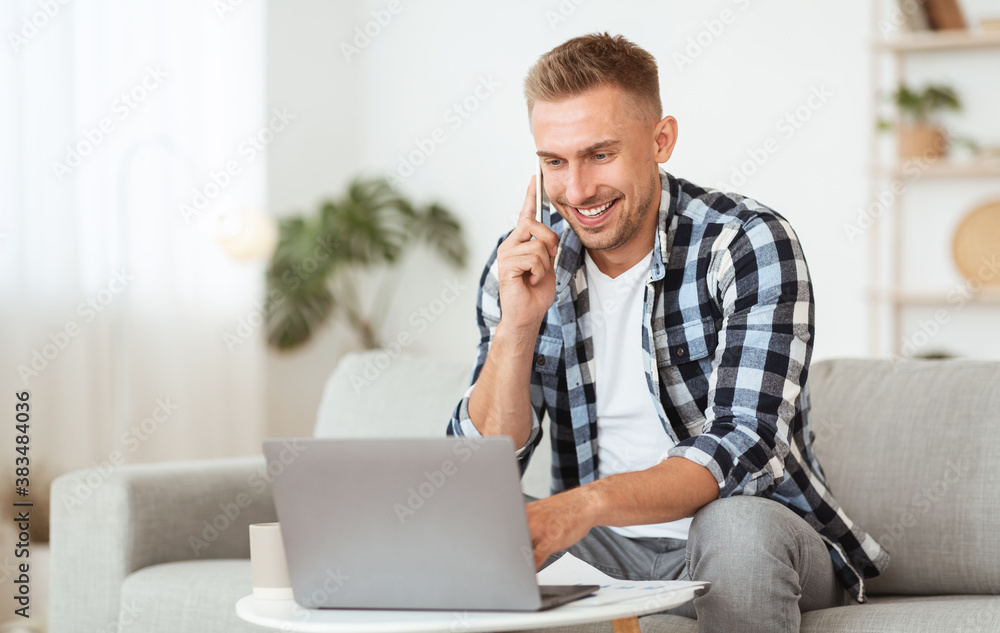 Portrait of successful smiling man using pc talking on cellphone