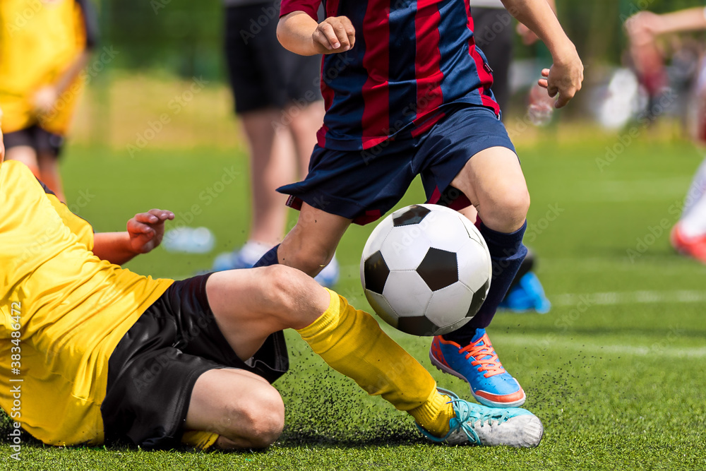 Obraz premium Soccer football tackle moment. Skill of tackling in soccer game. Two footballers in a duel. Running school age boys. Kids kicking soccer ball on grass pitch