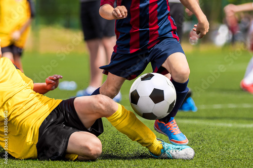 Soccer football tackle moment. Skill of tackling in soccer game. Two footballers in a duel. Running school age boys. Kids kicking soccer ball on grass pitch © matimix