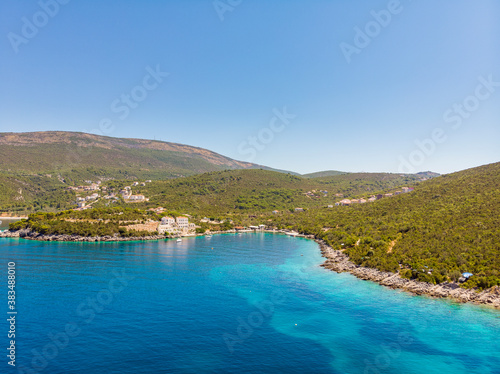 Rocky seaside near Veslo camping in Montenegro. Azure blue water, white waves hitting the rocks, sunny summer day, aerial drone view. Drone aerial shot