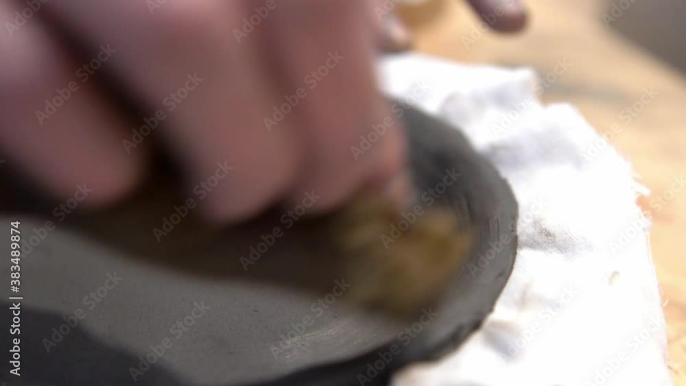 Smoothing out edges of clay dish with a wet sponge in a ceramics workshop, Handheld close up shot Smoothing out edges of clay dish with a wet sponge in a ceramics workshop, Handheld close up shot