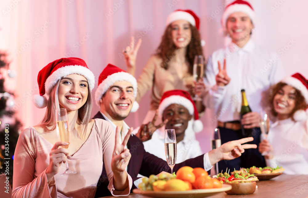 Friends Celebrating New Year Holding Glasses Gesturing V-Sign At Home