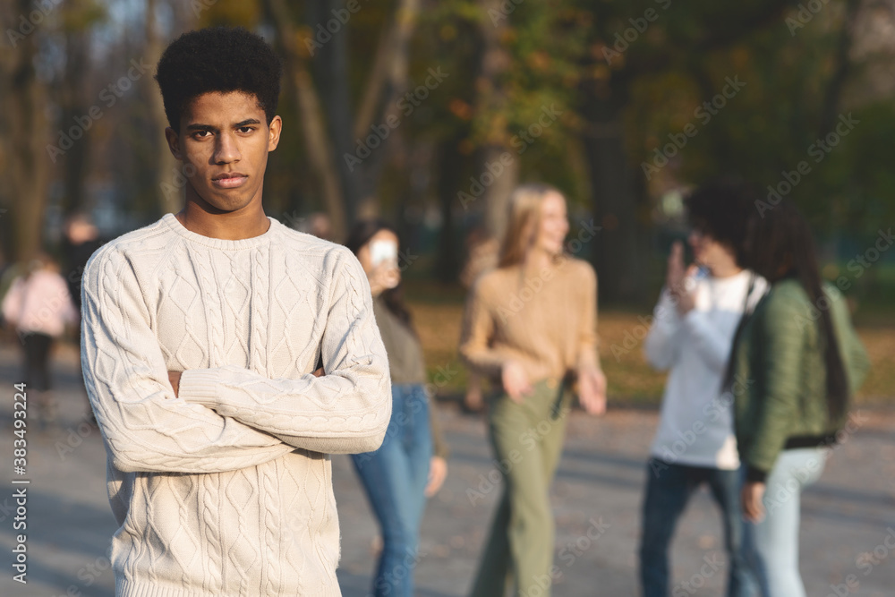 Depressed black guy standing apart from laughing students Depressed black guy standing apart from laughing students