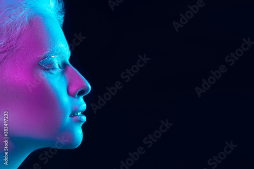 Feeling. Close up portrait of beautiful albino girl on dark background in neon light. Blonde female model with dreamlike make-up and well-kept skin. Concept of beauty, cosmetics, style, fashion.