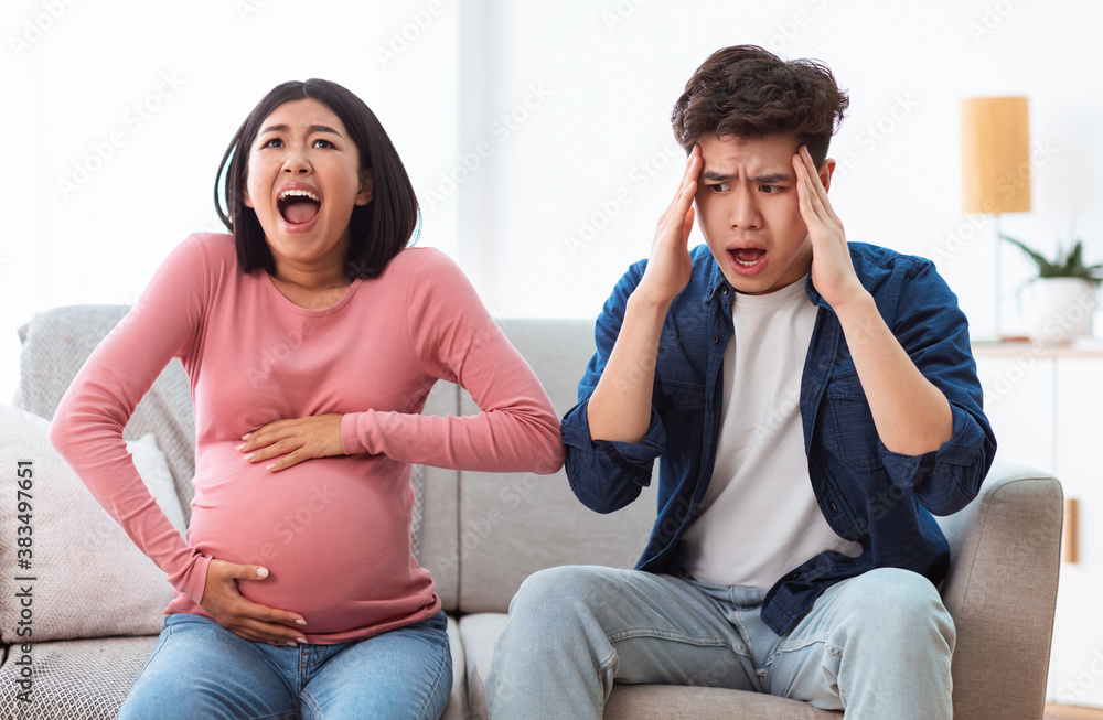 Pregnant Wife Shouting Touching Belly Sitting With Shocked Husband