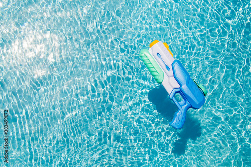 A child's blue water gun floats in the pool. A toy for playing in the pool or on the beach