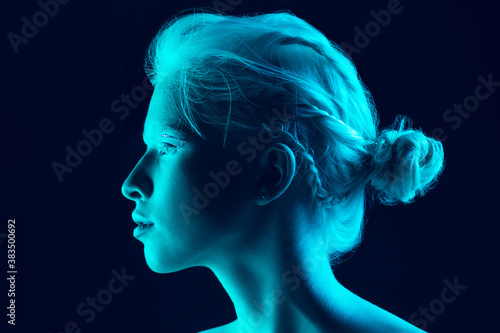 Night. Close up portrait of beautiful albino girl on dark background in neon light. Blonde female model with dreamlike make-up and well-kept skin. Concept of beauty, cosmetics, style, fashion.