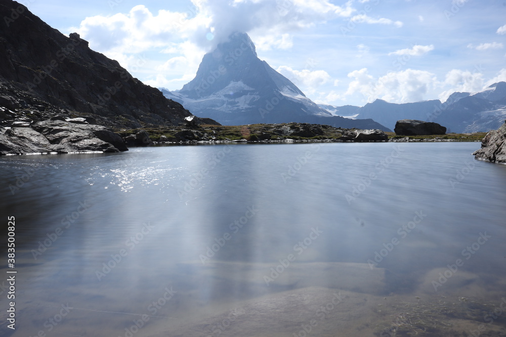 Calm, clear lake with the Matterhorn in the distance on a summer day in Switzerland.