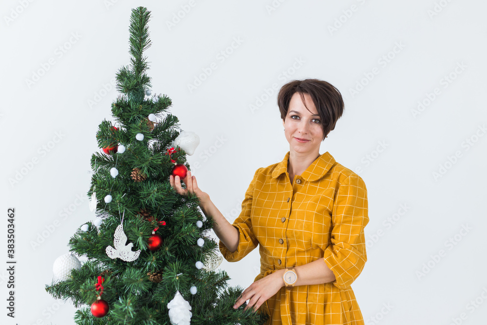 Portrait of smiling young woman decorating christmas tree. Holidays concept. Portrait of smiling young woman decorating christmas tree. Holidays concept.