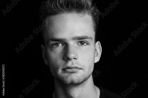 Obraz na płótnie Portrait of a serious young guy on a dark background, black and white photo w salonie